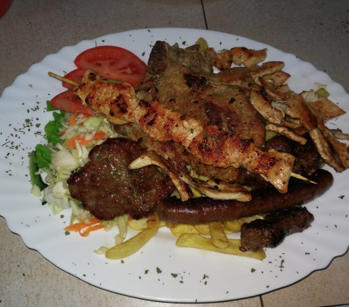 Barbecue dish with sausages, chicken and veal skewers, burgers and served with fries and salad.