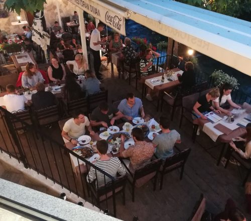 Groups of people seated on restaurant terrace in the evening.