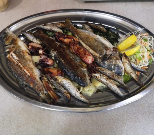 Fish plate with various types of fish served on metal plate.