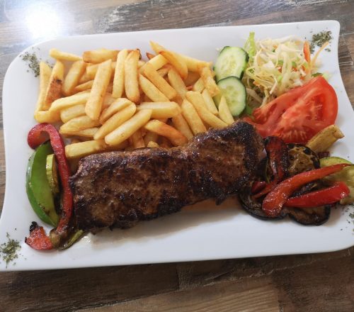 Steak with french fries, grilled vegetables and lettuce.