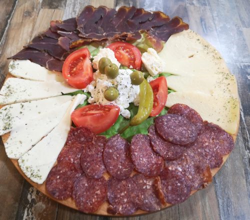 Appetizers plate served with different types of cheese, meat and toppings.
