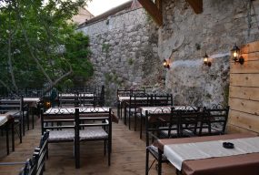 Restaurant terrace and outdoor seating with surrounding trees and old-style walls.