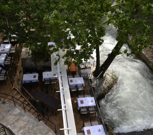 Bird view of restaurant terrace with a tree on side and a view on the river. 